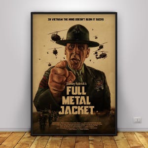 May include: A framed movie poster for Stanley Kubrick's "Full Metal Jacket." The poster features a stern-faced man in a military uniform pointing at the viewer, with helicopters in the background. The title is prominently displayed in bold letters.