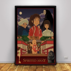 Op de afbeelding: Een ingelijste poster met personages uit de animatiefilm "Spirited Away". De illustratie toont een jong meisje in een rode outfit, samen met andere personages tegen een nachtelijke achtergrond. De titel "Spirited Away" staat onderaan.