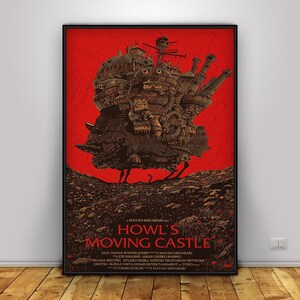 K&ouml;nnte beinhalten: Gerahmtes Poster des Animationsfilms "Das wandelnde Schloss". Das Kunstwerk zeigt das Schloss in Braun- und Beiget&ouml;nen vor rotem Hintergrund. Titel und Credits sind in braunem Text unten dargestellt.