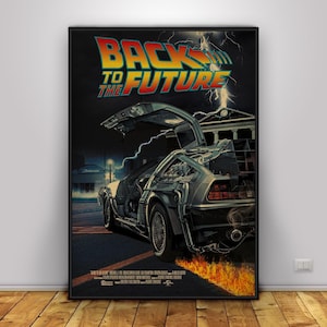 Pode incluir: Um poster emoldurado com o título do filme "BACK TO THE FUTURE" em laranja e amarelo. A imagem mostra o DeLorean com as portas abertas, chamas e raios contra um fundo escuro.
