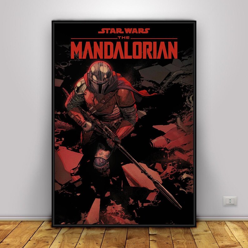 May include: A framed poster featuring a comic book style illustration of The Mandalorian from Star Wars. The Mandalorian is depicted in red and grey armour, holding a rifle. The poster's title, "STAR WARS THE MANDALORIAN," is in red text.