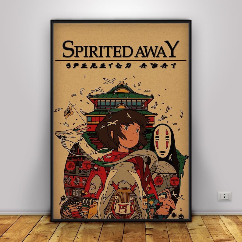 May include: A framed poster featuring the title "Spirited Away" in a bold, black font. The artwork showcases a young girl in a red outfit, surrounded by fantastical creatures and a traditional Japanese building, all set against a tan background.
