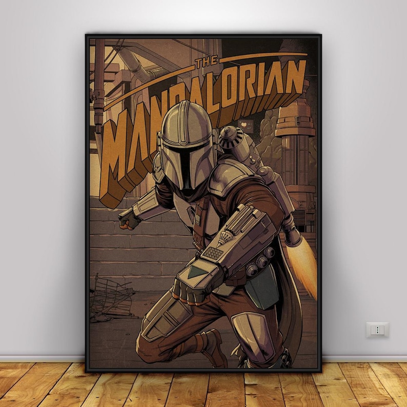 May include: A framed poster with a comic-style illustration of The Mandalorian. The character is shown crouching, wearing detailed armour and a helmet. The poster has a sepia tone, with the title "THE MANDALORIAN" across the top.