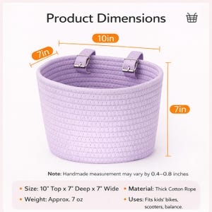 May include: A lavender cotton rope basket with two adjustable straps. The basket is 10 inches wide, 7 inches deep, and 7 inches high. The product dimensions are displayed in the image. The basket is designed to fit kids' bikes, scooters, and balance bikes.
