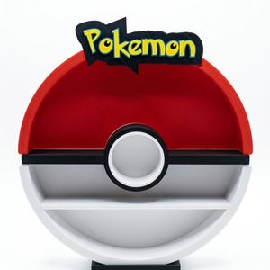 May include: A red, white, and black Pokemon-themed shelf unit. The top features the word "Pokemon" in yellow and black. The shelf has a circular design with two shelves and a white circle in the middle.
