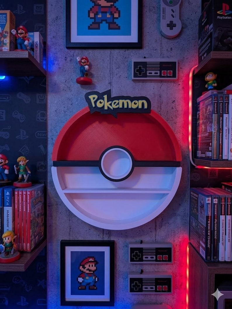 May include: A red, white, and black Pokemon-themed shelf, shaped like a Pokeball, mounted on a gray wall. The wall also features framed pixel art of Mario, Nintendo controllers, and figurines of video game characters. Shelves display video game cartridges and consoles.