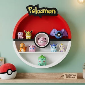 May include: A red, white, and black Pokemon-themed shelf shaped like a Poke Ball, displaying various Pokemon figurines. The shelf has a black "Pokemon" logo and is mounted on a light green wall. A Poke Ball plush and books are on a wooden shelf below.
