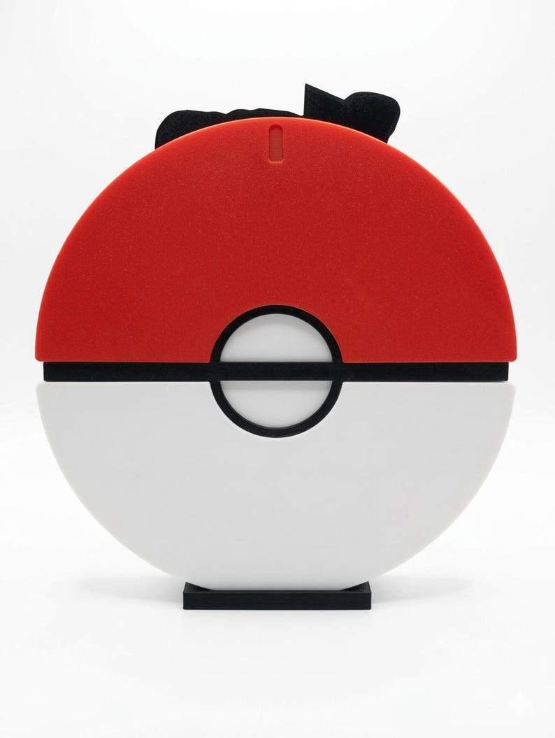 May include: A red and white sphere-shaped object with a black band and a black base. The top half is red, and the bottom half is white. A black bow-like shape is on top.