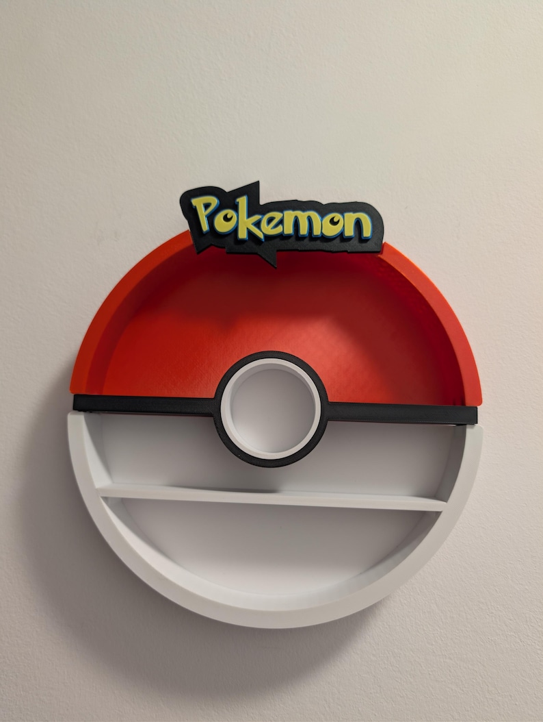 May include: A red, black, and white Pokemon-themed shelf with two levels. The top of the shelf has the word "Pokemon" in yellow and black. The shelf is round with a black circle in the middle.
