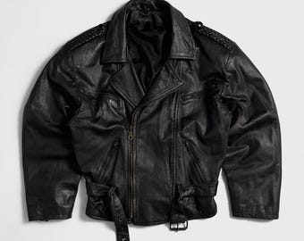 May include: A black leather motorcycle jacket featuring a wide notched collar, long sleeves with braided shoulder detailing, and a front zipper closure. The jacket includes multiple zippered pockets, a buckled waist belt, and a smooth black lining.