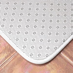 May include: A white rectangular floor mat featuring a repeating pattern of small black flower-shaped dots across the surface. The mat has a smooth white fabric border and a textured underside designed for grip on flat surfaces.