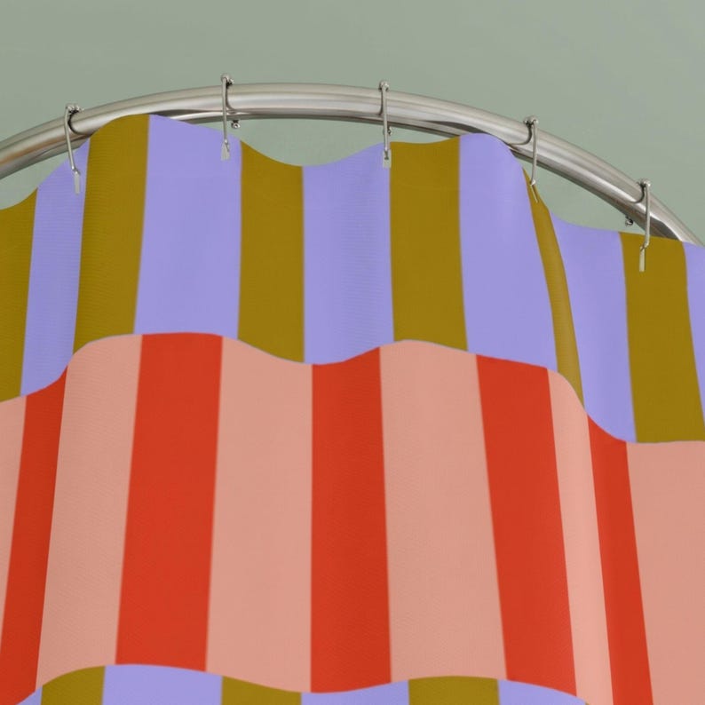 Pu&ograve; includere: Una tenda da doccia appesa a un'asta metallica curva con anelli argentati. Il tessuto presenta un motivo a righe verticali ripetute con bande alternate nei colori viola chiaro, giallo senape, arancione brillante e pesca tenue.