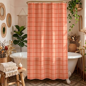 May include: A peach-colored shower curtain featuring a grid pattern of thin, vibrant orange lines. The curtain hangs from a gold-toned rod and is positioned in front of a white clawfoot bathtub with gold-toned hardware in a bathroom setting.