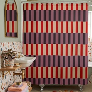 May include: A shower curtain featuring a repeating vertical block pattern in alternating columns of bright red, muted mauve, and cream. The fabric hangs from a metal rod with rings, displaying a consistent geometric design across the entire surface.