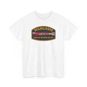 May include: White t-shirt featuring a graphic with the word "WARGASM" in gold lettering above a row of flags. Below the graphic, the text reads "SAME SHIT DIFFERENT CENTURY".