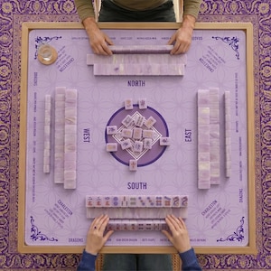 May include: A complete Mahjong set with lavender tiles and a matching playing surface. The game board is surrounded by a wooden frame and features the words "North", "South", "East", and "West". The set includes tiles, and is ready to play.