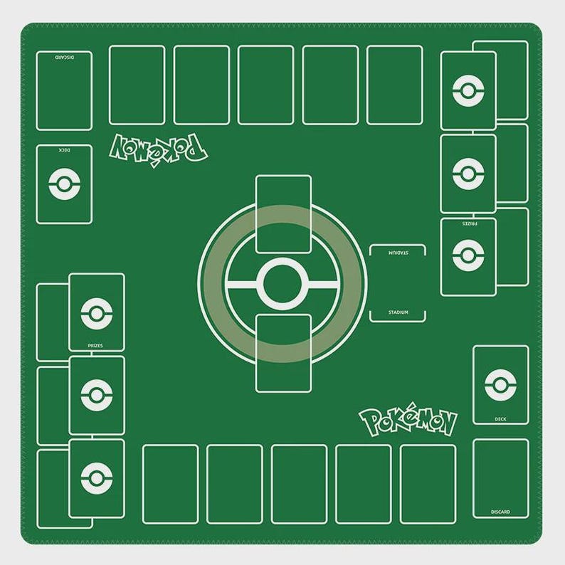 May include: A green Pok&eacute;mon playmat with white outlines and text. The mat features designated areas for cards, including deck, prizes, and discard zones. The Pok&eacute;mon logo is prominently displayed, along with a central play area.