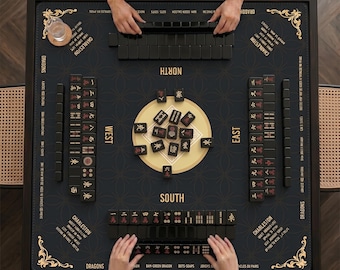 May include: A black Mahjong game set with gold accents. The game board is square with a dark surface and decorative corner designs. The set includes black tiles, and the game is being played by multiple people.