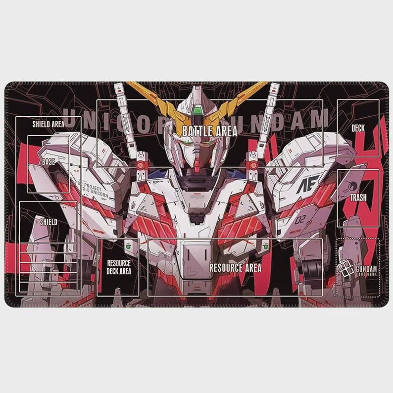 May include: A black and red playmat featuring a detailed illustration of a Gundam robot. The mat includes labeled areas for gameplay, such as "Battle Area," "Deck," and "Resource Area." The robot is white, red, and gold, with the text "UNICORN GUNDAM" across the top.