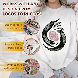May include: A white crewneck sweatshirt featuring a black graphic of two otters swimming in a circle around a pink oval with small fish. Three circular insets show fabric transfers, an iron pressing a design, and various printed sheets.