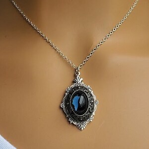 Peut inclure: Un collier en cha&icirc;ne argent avec un pendentif orn&eacute; d'une pierre ovale bleue et noire dans un cadre argent&eacute;.