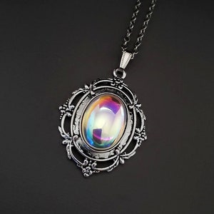 Pode incluir: Um colar de prata com um pingente oval iridescente engastado em uma moldura de filigrana.