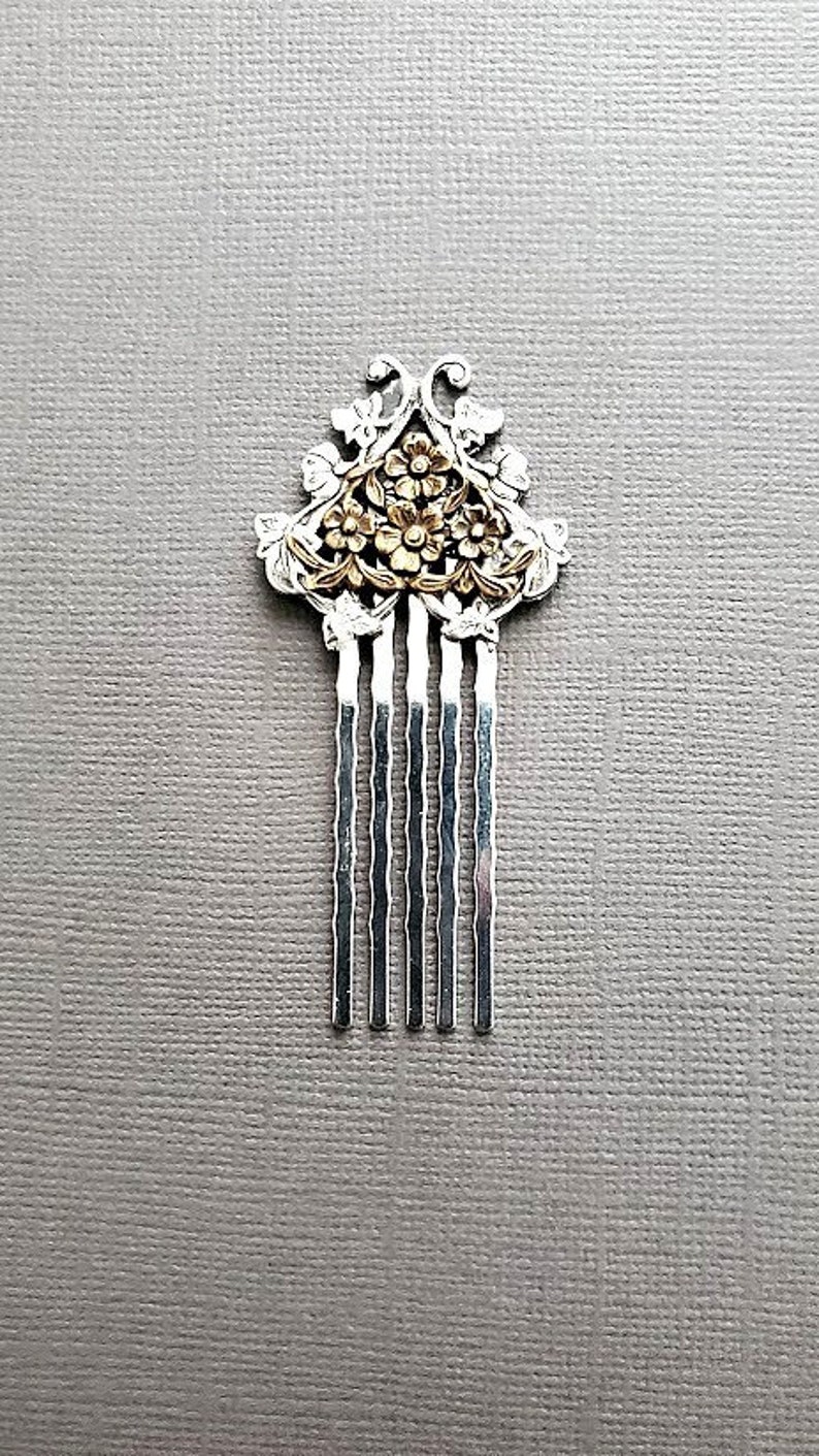May include: Silver hair comb with a gold floral design. The comb has five tines.