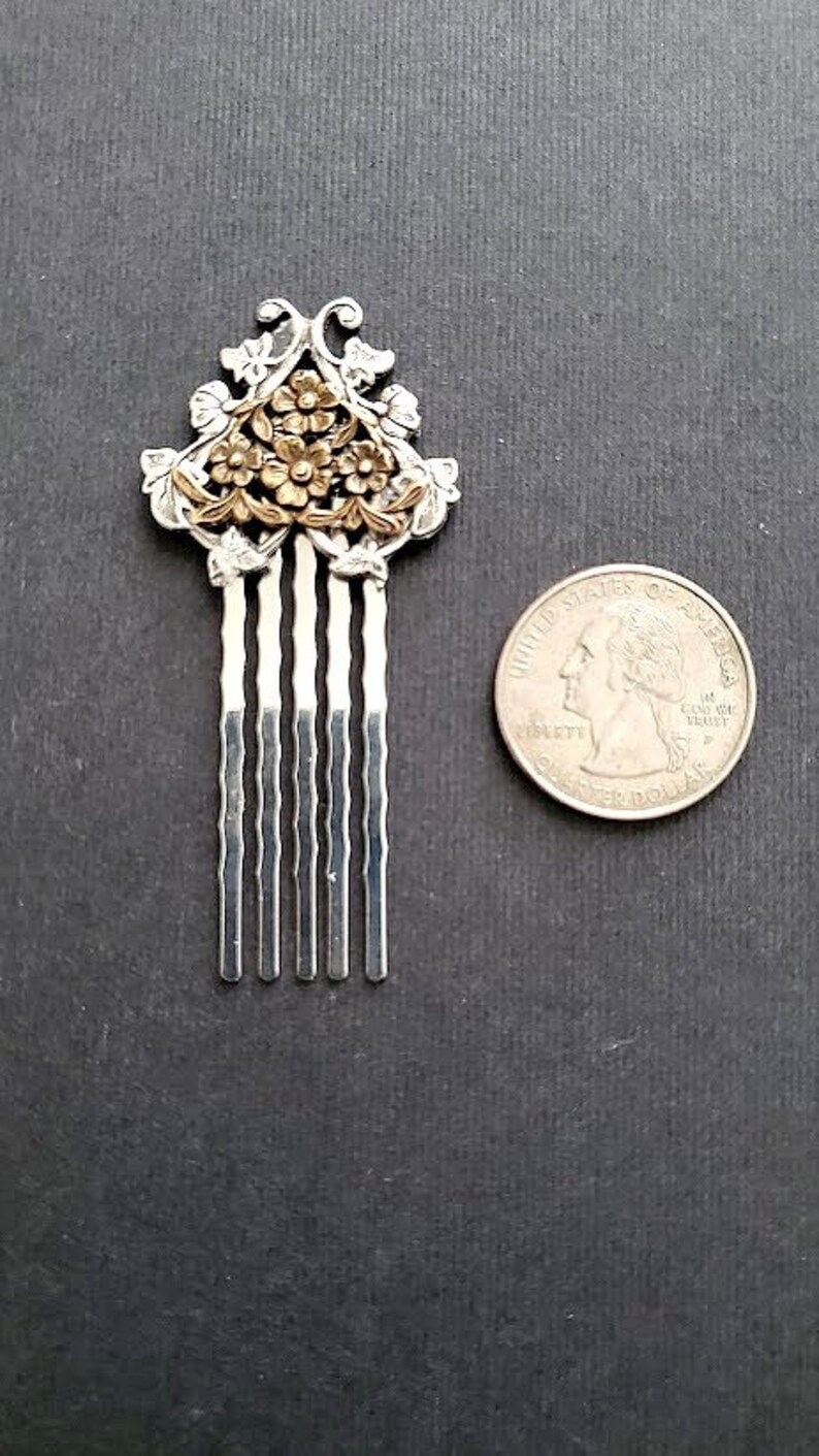 May include: Silver hair comb with a floral design in gold. The comb has five tines.