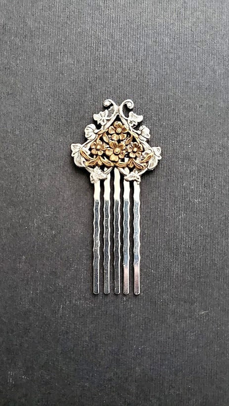 May include: A silver hair comb with a gold floral design. The comb has seven tines.