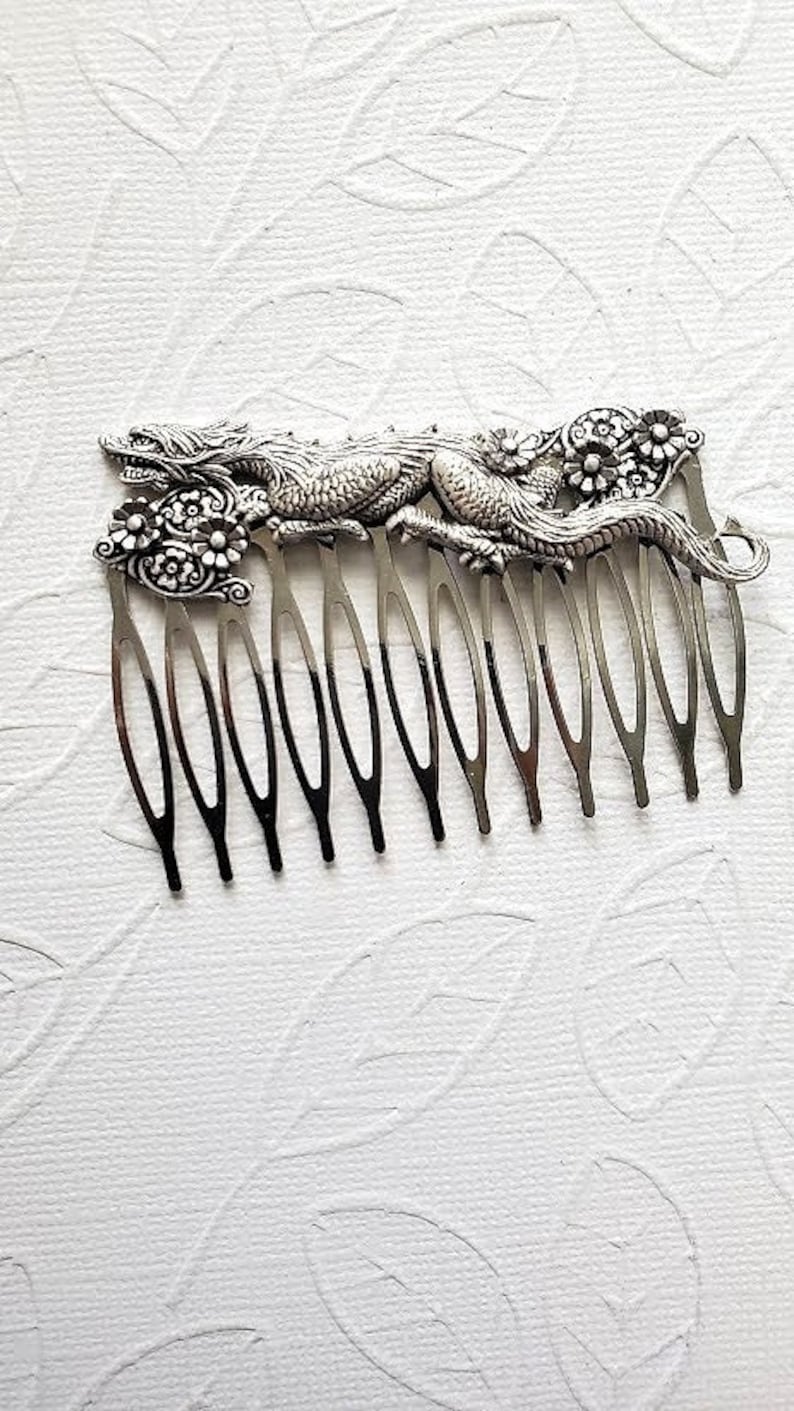 May include: Silver hair comb with a detailed dragon design and floral accents.