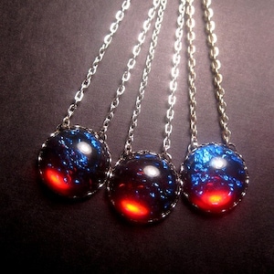 May include: Three silver chains with blue and red iridescent glass pendants. The pendants are round and have a silver rim.