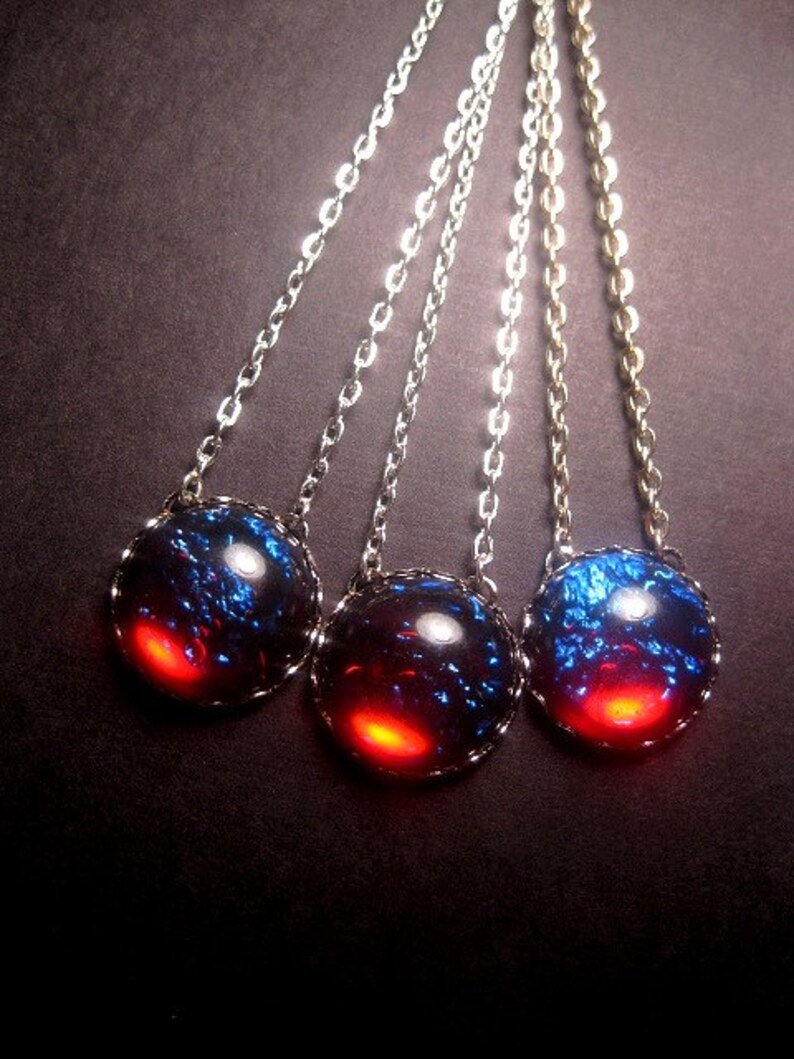 May include: Three silver chains with blue and red iridescent glass pendants. The pendants are round and have a silver rim.