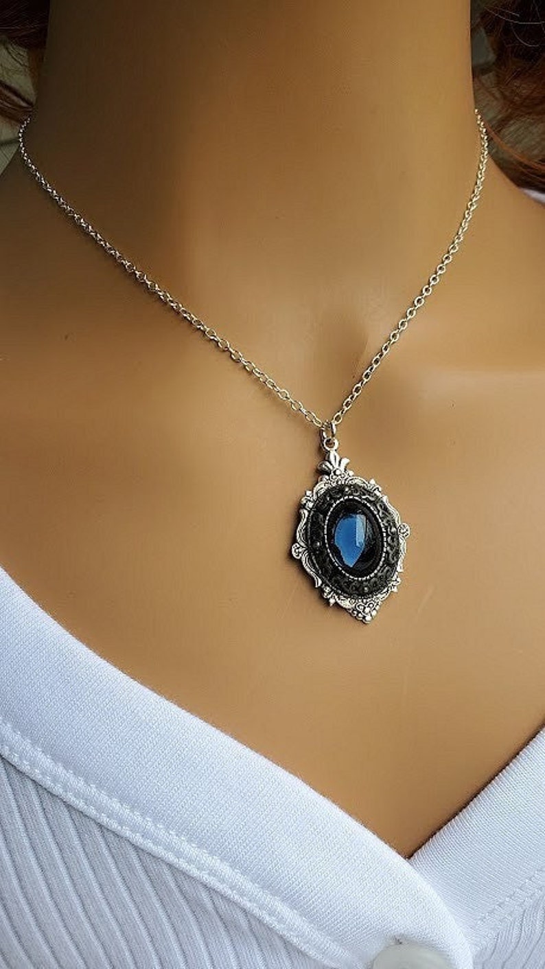 Peut inclure: Un collier en cha&icirc;ne argent avec un pendentif orn&eacute; d'une pierre pr&eacute;cieuse bleue sertie dans un cadre en filigrane argent.