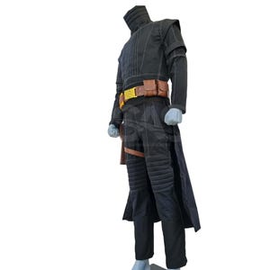 May include: A black long-sleeved jacket and matching trousers with white contrast stitching, featuring a high collar, padded shoulder and knee sections, a brown leather utility belt with pouches, and a long coat tail extending from the waist.