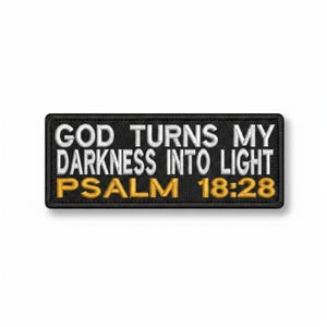 May include: A black rectangular patch featuring white embroidered text: "GOD TURNS MY DARKNESS INTO LIGHT" and gold text: "PSALM 18:28". The patch has a black border.