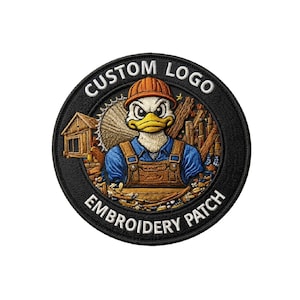 May include: Circular embroidered patch featuring a cartoon duck in a hard hat and overalls, set against a backdrop of wood and a small building. The patch has the text "CUSTOM LOGO" and "EMBROIDERY PATCH" in white on a black background.