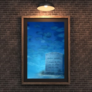 Puede incluir: Obra de arte enmarcada que representa una lápida sumergida en agua, con nenúfares y flores. La lápida dice "JIMMY HOFFA" con fechas de nacimiento y defunción. La obra de arte está enmarcada en un marco de madera oscura.