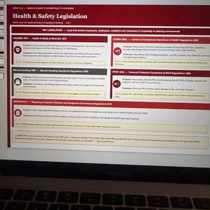 May include: A laptop screen displaying a document titled "Health & Safety Legislation." The document outlines key legislation like HASAWA 1974 and COSHH 2002, with sections on employer and employee responsibilities. The screen shows a keyboard below.