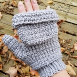 May include: A light gray, crocheted fingerless glove with a folded cuff. The glove is made of a textured yarn and has a ribbed cuff. The image includes the text "Crystallized Designs" in the upper right corner.