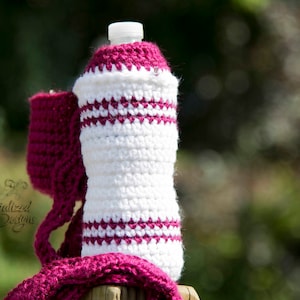 Op de afbeelding: Een witte en roze gehaakte fleshoes met een wit en roze gestreept patroon. De hoes is gemaakt van zacht garen en is perfect om je drankjes koud of warm te houden.