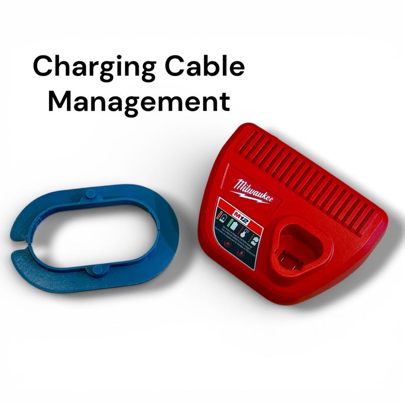 May include: A red Milwaukee M12 battery charger and a blue oval-shaped plastic ring. The text Charging Cable Management is displayed above the items. The charger features a vented top surface and a label with battery status icons.