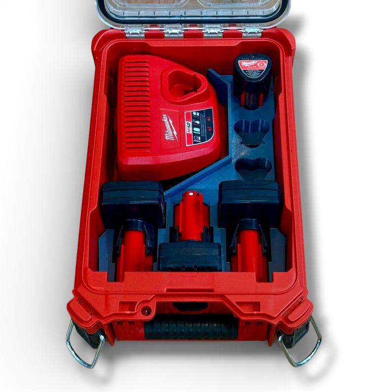 May include: Red Milwaukee M12 power tool kit in a red case. The case contains a charger, batteries, and other accessories. The case has a clear lid and metal latches. The Milwaukee logo is visible on the charger.