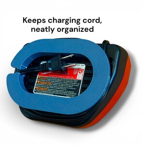 May include: A black and orange battery charger featuring a blue plastic cord organizer attachment. The device includes a black power cord and a label with the text: Keeps charging cord, neatly organized, along with safety warnings.