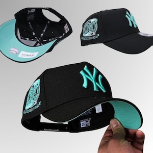 May include: Black baseball cap with a teal underbill and teal embroidered logo. The cap features a 35th Anniversary Subway Series patch on the side. The New Era 9FORTY adjustable hat is a classic baseball cap style.