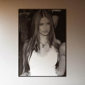 Può includere: Una camera da letto con un grande ritratto in bianco e nero incorniciato di una donna sopra un letto. Il letto ha un piumino grigio scuro e cuscini chiari. Grandi finestre lasciano entrare la luce naturale.