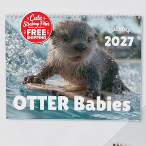 Może przedstawiać: Kalendarz ścienny na 2027 rok ze zdjęciem mokrego małego wydry surfującego na małej drewnianej desce na falach oceanu. Tekst na okładce brzmi "Cute Stocking Filler FREE SHIPPING", "CALENDAR 2027" oraz "OTTER Babies" białą czcionką.