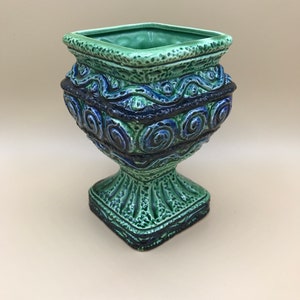 Peut inclure: Un pot en céramique vert et bleu avec une base carrée et un motif décoratif de motifs tourbillonnants.