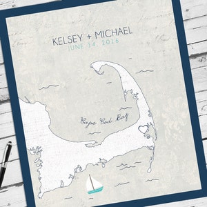 May include: A framed print featuring a map of Cape Cod, Massachusetts, with the names "KELSEY + MICHAEL" and the date "JUNE 14, 2016" in blue. A small sailboat is depicted near the coast. The print has a blue border.