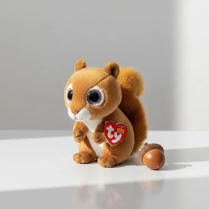 May include: A soft, brown squirrel toy with big eyes and a bushy tail. It has a red heart-shaped tag and a small, brown acorn. The toy is designed as a collectible item, perfect for children or collectors.