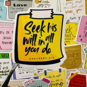 May include: A yellow sticker with the text "Seek his Will in all you do" in black script. The sticker is surrounded by other colourful stickers with various inspirational quotes and phrases.